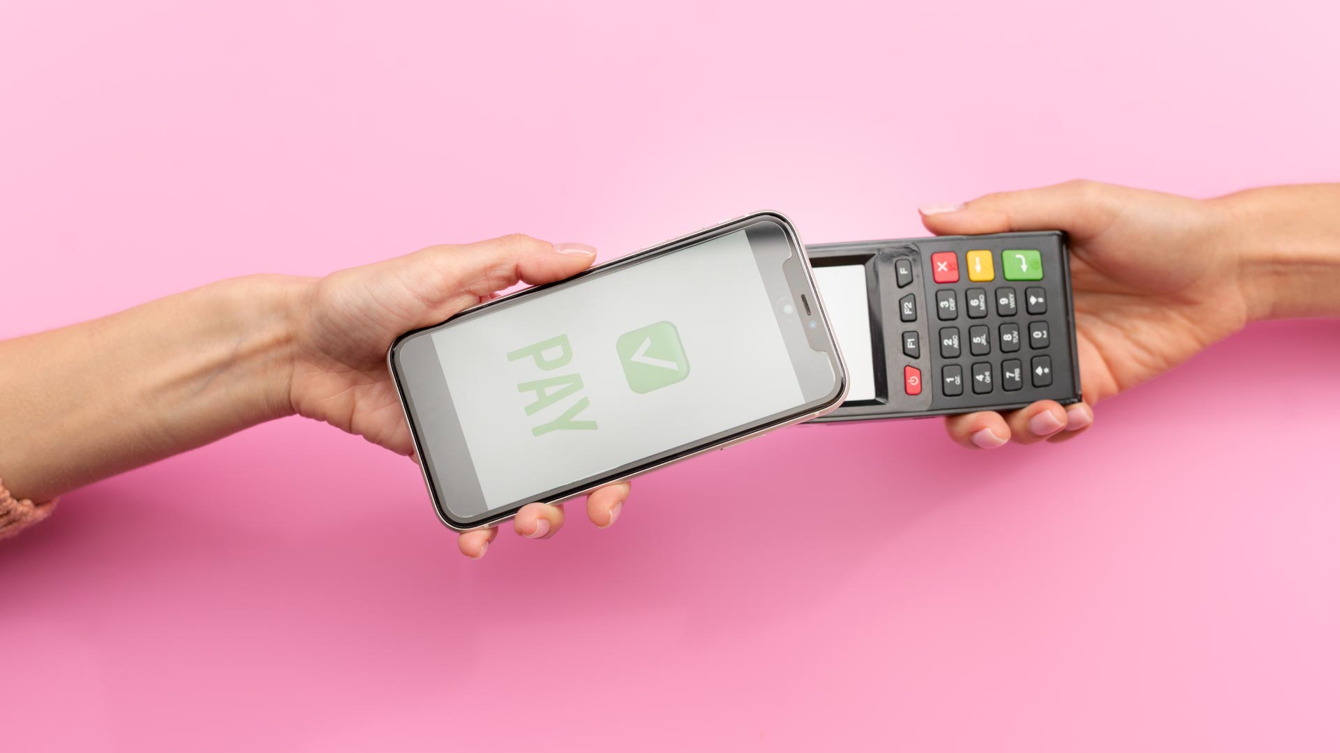 Pessoa realizando pagamento por aproximação com smartphone em máquina de cartão, sobre fundo rosa.