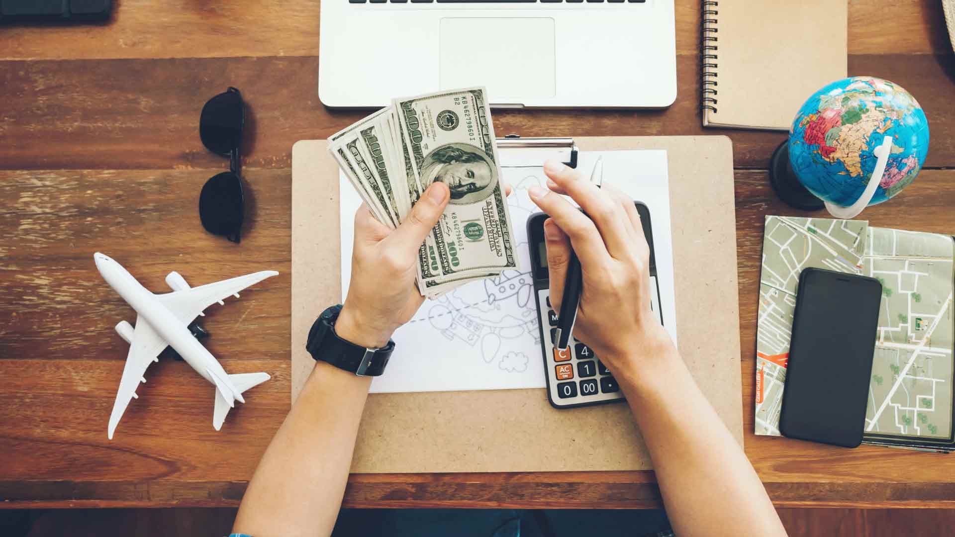 Pessoa calculando despesas em dólar com notas na mão, simbolizando pagamento cross-border.