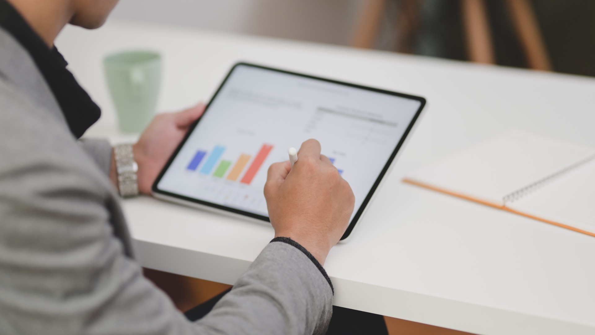 Pessoa utilizando uma caneta digital para analisar gráficos de desempenho em um tablet, representando a estratégia de Next Best Offer através da análise de dados para a personalização de ofertas e antecipação das necessidades do cliente.