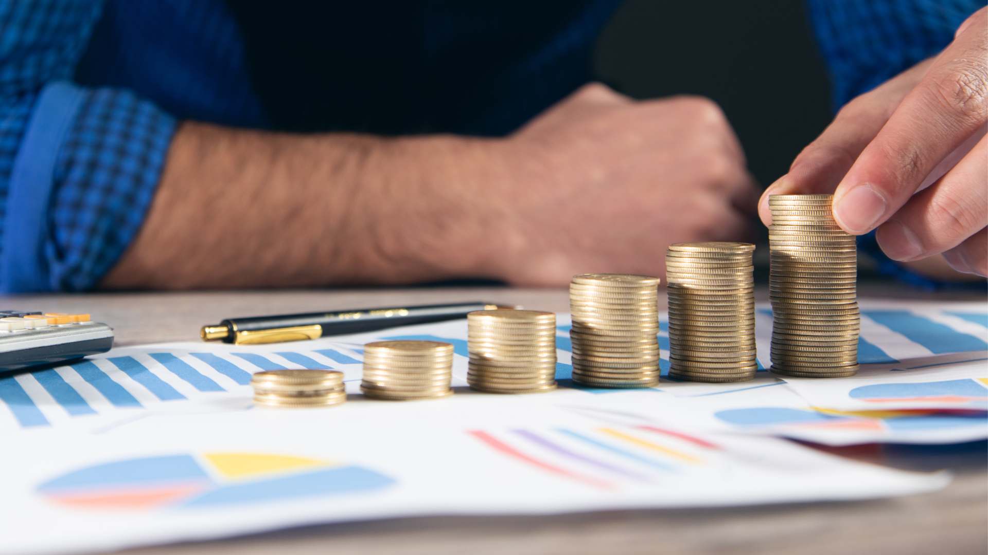 Pilhas de moedas organizadas em crescimento sobre gráficos financeiros, representando o mercado de crédito, análise de dados e evolução de investimentos.